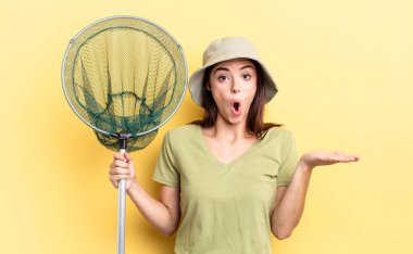 Genç İspanyol kadın şaşırmış ve şok olmuş görünüyor, çenesi düşmüş bir nesne balık ağı kavramını elinde tutuyor