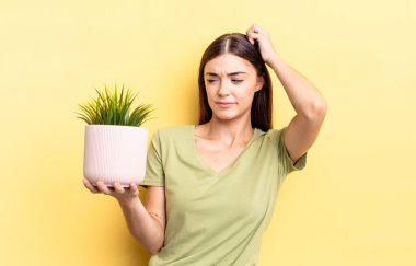 Genç İspanyol kadın şaşkın ve kafası karışık, kaşınan bir kafa hissediyor. bitki otu konsepti