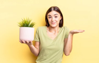 Genç İspanyol kadın şaşkın, şaşkın ve şüpheci hissediyor. bitki otu konsepti