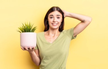 Genç İspanyol kadın stresli, endişeli ya da korkmuş hissediyor, elleri başının üstünde. bitki otu konsepti