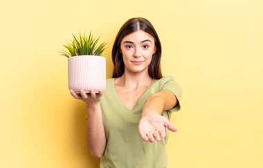 Genç İspanyol kadın mutlu bir şekilde gülümsüyor ve bir konsept sunuyor. bitki otu konsepti