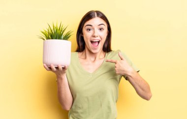 Genç İspanyol kadın kendini mutlu hissediyor ve heyecanla kendini işaret ediyor. bitki otu konsepti