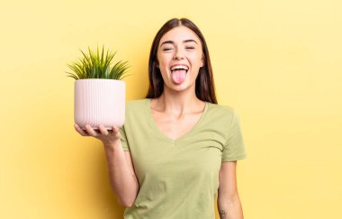 Neşeli ve asi tavırları olan, şaka yapan ve dilini dışarı çıkaran genç İspanyol bir kadın. bitki otu konsepti