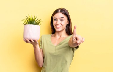 Genç İspanyol kadın gururla gülümsüyor ve kendinden emin bir numara oluyor. bitki otu konsepti