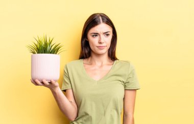 Genç İspanyol kadın üzgün, üzgün ya da kızgın hissediyor ve yana bakıyor. bitki otu konsepti