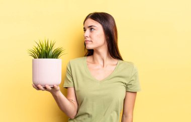 Profil görünümlü genç İspanyol kadın hayal mi kuruyor yoksa hayal mi kuruyor? bitki otu konsepti