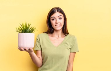 Genç İspanyol kadın şaşkın ve şaşkın görünüyor. bitki otu konsepti