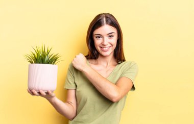 Genç İspanyol kadın kendini mutlu hissediyor ve bir meydan okumayla yüzleşiyor ya da kutluyor. bitki otu konsepti