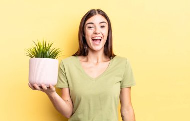 Genç İspanyol kadın mutlu ve hoş bir şekilde şaşırmış görünüyor. bitki otu konsepti