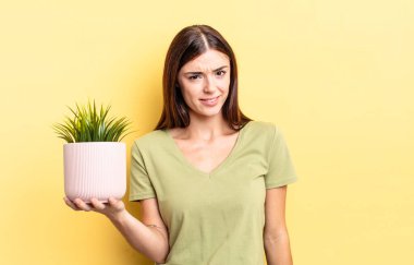 Genç İspanyol kadın şaşkın ve şaşkın hissediyor. bitki otu konsepti