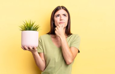 Genç İspanyol kadın düşünüyor, kuşkulu ve şaşkın hissediyor. bitki otu konsepti