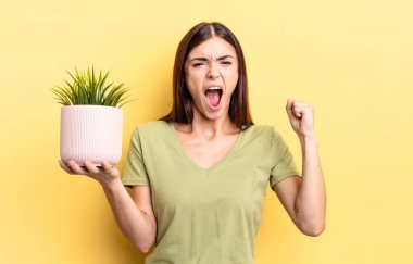 Genç İspanyol kadın öfkeli bir ifadeyle agresif bir şekilde bağırıyor. bitki otu konsepti