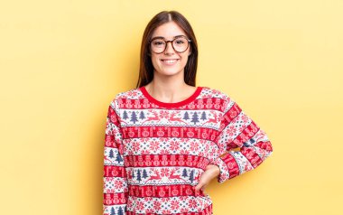 Genç İspanyol kadın mutlu bir şekilde gülümsüyor, eli kalçasında ve kendinden emin. Chistmas ve yeni yıl konsepti