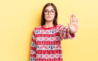 Genç İspanyol kadın ciddi görünüyor. Avuç içini gösteriyor. Durdurma hareketi yapıyor. Chistmas ve yeni yıl konsepti