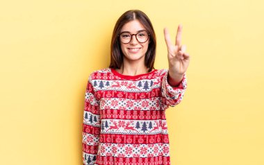 Genç İspanyol kadın gülümsüyor ve arkadaş canlısı görünüyor, iki numarayı gösteriyor. Chistmas ve yeni yıl konsepti