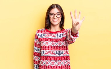 Genç İspanyol kadın gülümsüyor ve arkadaş canlısı görünüyor, dört numarayı gösteriyor. Chistmas ve yeni yıl konsepti