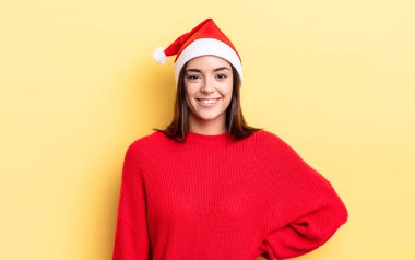 Genç İspanyol kadın mutlu bir şekilde gülümsüyor, eli kalçasında ve kendinden emin. Chistmas ve yeni yıl konsepti