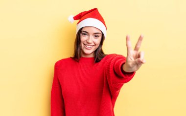 Genç İspanyol kadın gülümsüyor ve mutlu görünüyor, zafer ya da barış işareti yapıyor. Chistmas ve yeni yıl konsepti