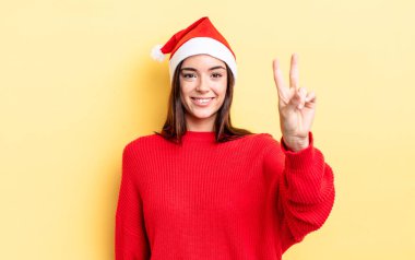 Genç İspanyol kadın gülümsüyor ve arkadaş canlısı görünüyor, iki numarayı gösteriyor. Chistmas ve yeni yıl konsepti