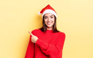 Genç İspanyol kadın neşeyle gülümsüyor, mutlu hissediyor ve bir tarafı işaret ediyor. Chistmas ve yeni yıl konsepti