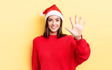 Genç İspanyol kadın gülümsüyor ve arkadaş canlısı görünüyor, beş numarayı gösteriyor. Chistmas ve yeni yıl konsepti