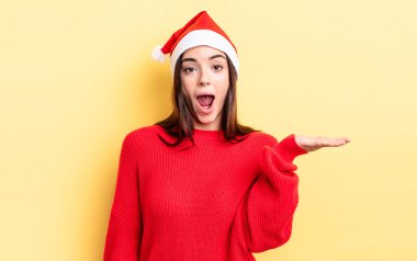 Genç İspanyol kadın şaşırmış ve şok olmuş görünüyor. Çenesi düşmüş ve elinde bir nesne tutuyor. Chistmas ve yeni yıl konsepti