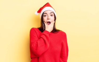 Ağzı ve gözleri sonuna kadar açık ve eli çenesinde olan genç İspanyol kadın. Chistmas ve yeni yıl konsepti