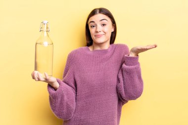 Genç İspanyol kadın şaşkın, şaşkın ve şüpheci hissediyor. su şişesi kavramı