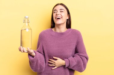 Genç İspanyol kadın komik bir şakaya yüksek sesle gülüyor. su şişesi kavramı