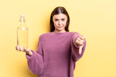 Latin kökenli genç bir kadın kızmış, baş parmağını kaldırmış. su şişesi kavramı