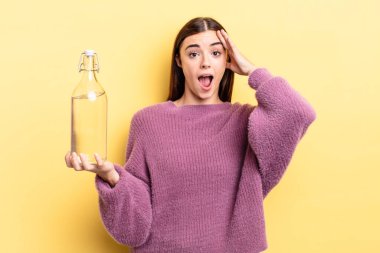 Genç İspanyol kadın mutlu, şaşkın ve şaşırmış görünüyor. su şişesi kavramı