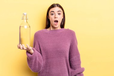 Genç İspanyol kadın çok şaşırmış ya da şok olmuş görünüyor. su şişesi kavramı