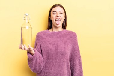 Neşeli ve asi tavırları olan, şaka yapan ve dilini dışarı çıkaran genç İspanyol bir kadın. su şişesi kavramı