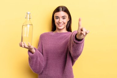 Genç İspanyol kadın gururla gülümsüyor ve kendinden emin bir numara oluyor. su şişesi kavramı