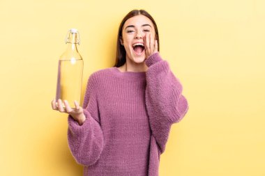 Genç İspanyol kadın kendini mutlu hissediyor, elleri ağzının kenarında bağırıyor. su şişesi kavramı