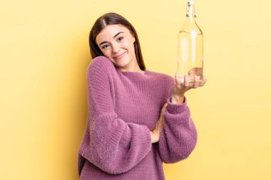 Genç İspanyol kadın omuz silkiyor, kafası karışık ve kararsız. su şişesi kavramı