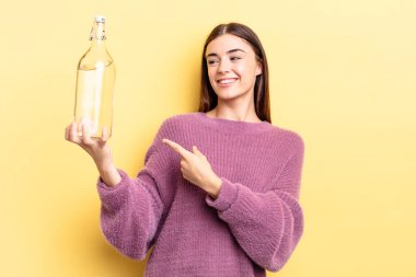 Genç İspanyol kadın neşeyle gülümsüyor, mutlu hissediyor ve bir tarafı işaret ediyor. su şişesi kavramı