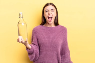 Genç İspanyol kadın agresif bir şekilde bağırıyor, çok kızgın görünüyor. su şişesi kavramı