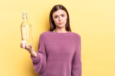 Genç İspanyol kadın üzgün ve mızmızlanıyor. Mutsuz bir bakışı var ve ağlıyor. su şişesi kavramı