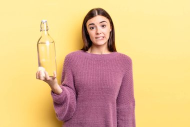 Genç İspanyol kadın şaşkın ve şaşkın görünüyor. su şişesi kavramı