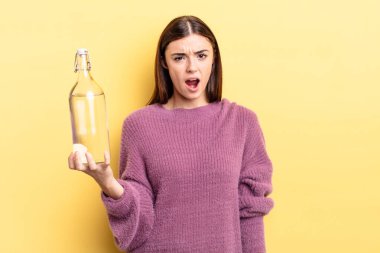 Genç İspanyol kadın şaşkın ve şaşkın hissediyor. su şişesi kavramı