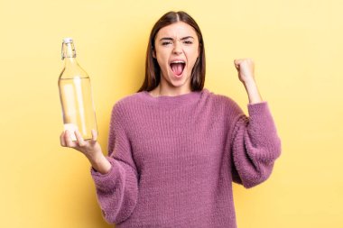 Genç İspanyol kadın öfkeli bir ifadeyle agresif bir şekilde bağırıyor. su şişesi kavramı