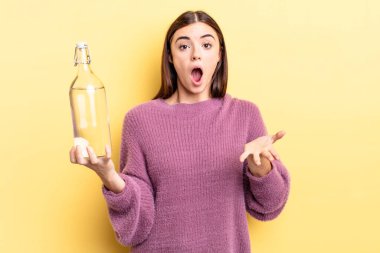 Genç İspanyol kadın şok olmuş ve şaşırmış hissediyor. su şişesi kavramı