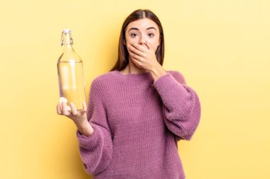 Genç İspanyol kadın şok olmuş ellerle ağzını kapatıyor. su şişesi kavramı