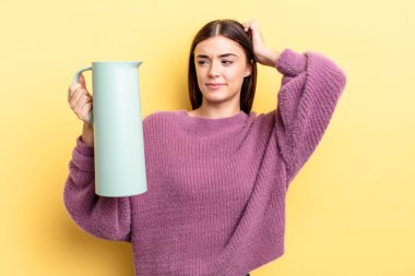 Genç İspanyol kadın mutlu bir şekilde gülümsüyor ve hayal kuruyor ya da şüphe ediyor. Kahve termosu kavramı