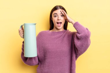 Genç İspanyol kadın mutlu, şaşkın ve şaşırmış görünüyor. Kahve termosu kavramı