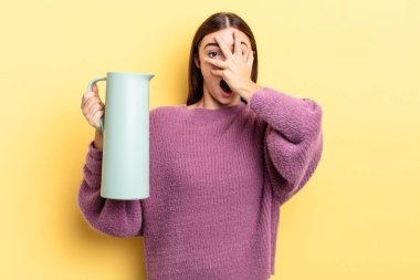 Genç İspanyol bir kadın şok olmuş, korkmuş ya da korkmuş görünüyor. Yüzü elle kapatılmış. Kahve termosu kavramı