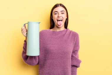 Neşeli ve asi tavırları olan, şaka yapan ve dilini dışarı çıkaran genç İspanyol bir kadın. Kahve termosu kavramı