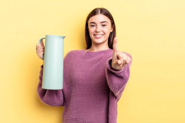 Genç İspanyol kadın gururla gülümsüyor ve kendinden emin bir numara oluyor. Kahve termosu kavramı