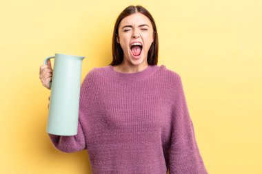 Genç İspanyol kadın agresif bir şekilde bağırıyor, çok kızgın görünüyor. Kahve termosu kavramı